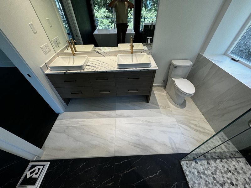 Light marble-look porcelain bathroom floor with dark double vanity, vessel sinks and modern toilet