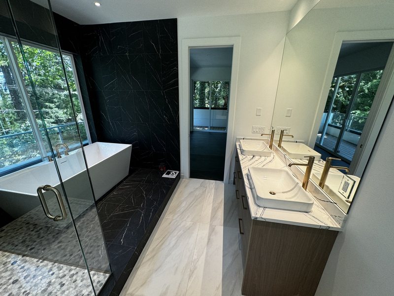Complete primary bathroom with glass shower, freestanding tub, double vanity and contrasting porcelain tile