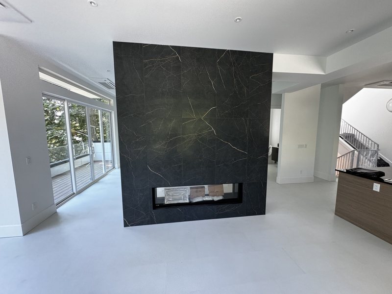 Open-plan interior with a floor-to-ceiling black porcelain fireplace wall and linear gas insert