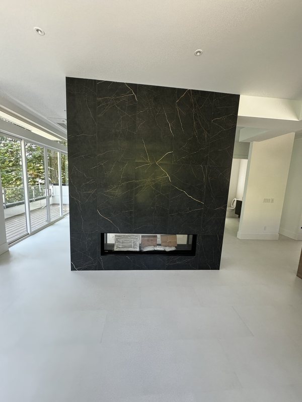 Front view of a modern linear fireplace set into a tall black porcelain feature wall