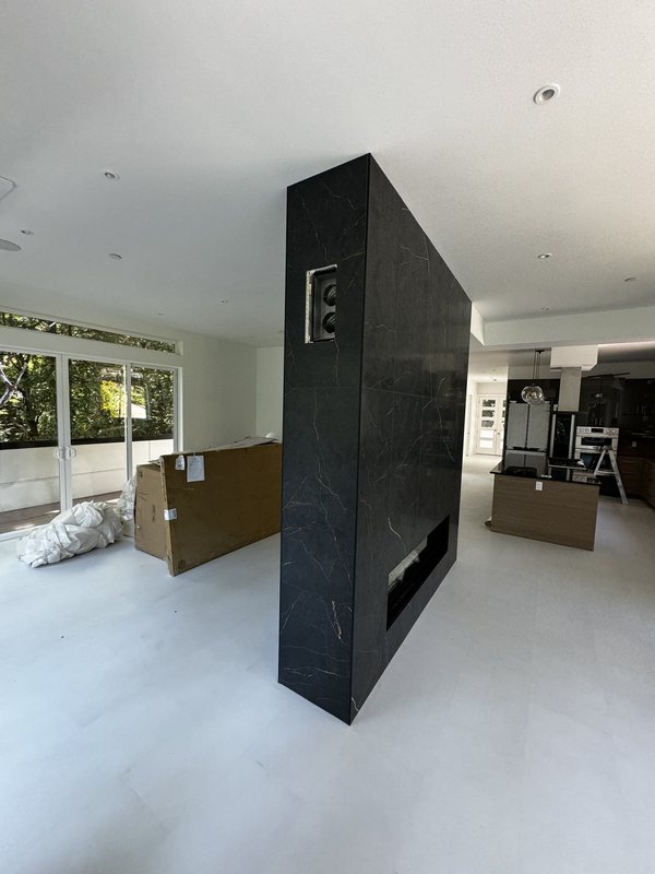 Side view of a black porcelain fireplace partition connecting an open living and kitchen interior