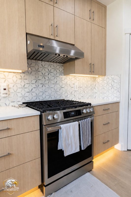 Natural-wood kitchen with white island countertop, pendant lights and coordinated cabinetry, view 10 of 20