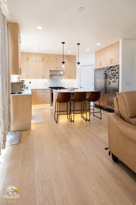 Natural-wood kitchen with white island countertop, pendant lights and coordinated cabinetry, view 13 of 20