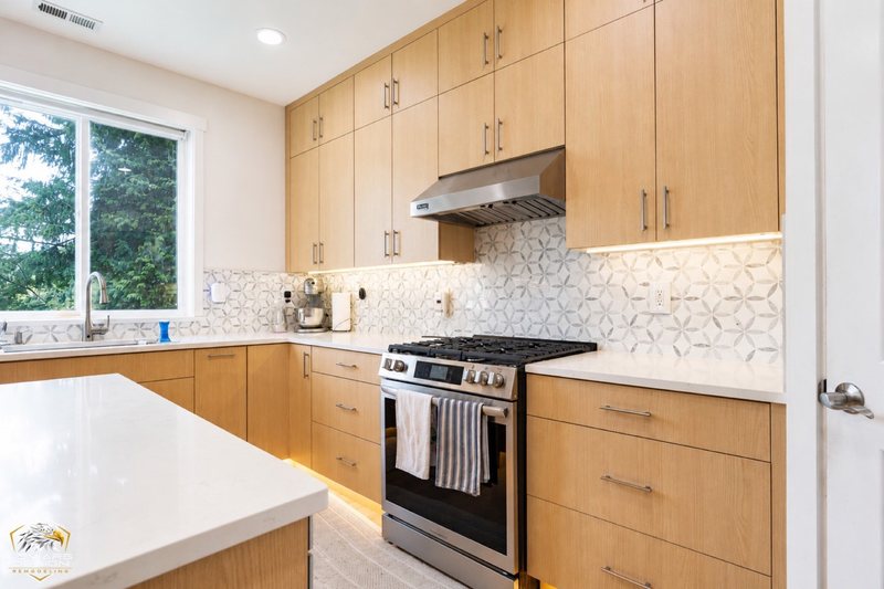 Natural-wood kitchen with white island countertop, pendant lights and coordinated cabinetry, view 16 of 20