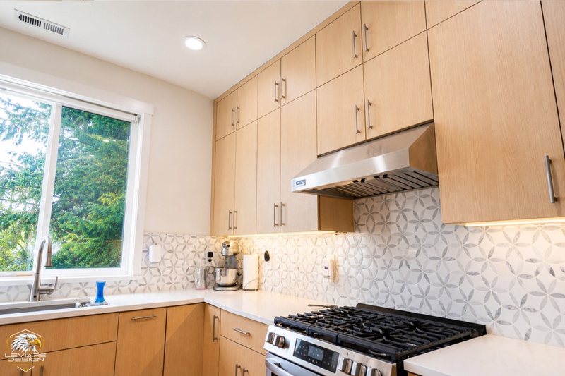 Natural-wood kitchen with white island countertop, pendant lights and coordinated cabinetry, view 17 of 20