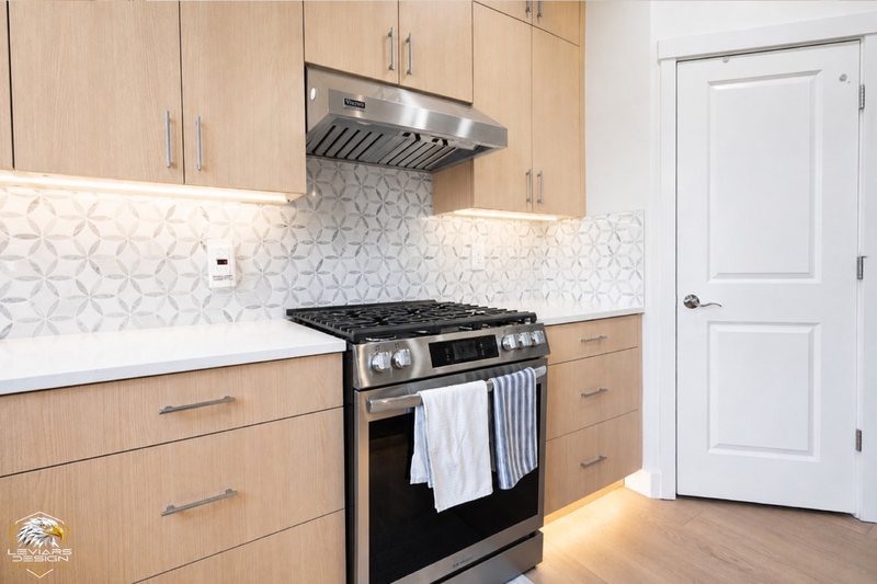 Natural-wood kitchen with white island countertop, pendant lights and coordinated cabinetry, view 18 of 20