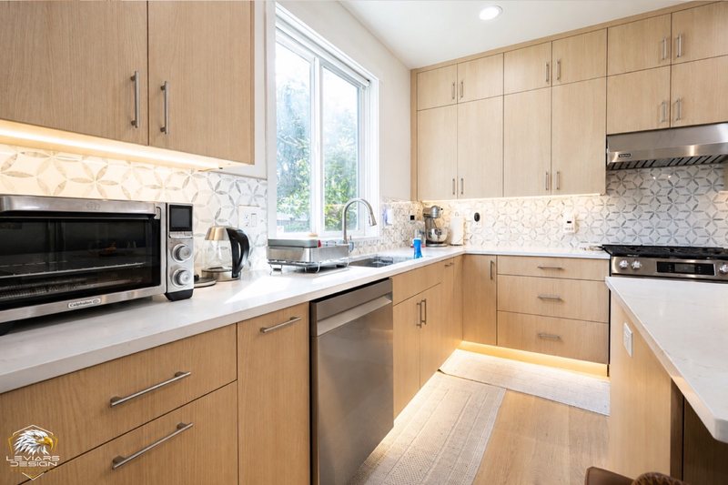 Natural-wood kitchen with white island countertop, pendant lights and coordinated cabinetry, view 19 of 20