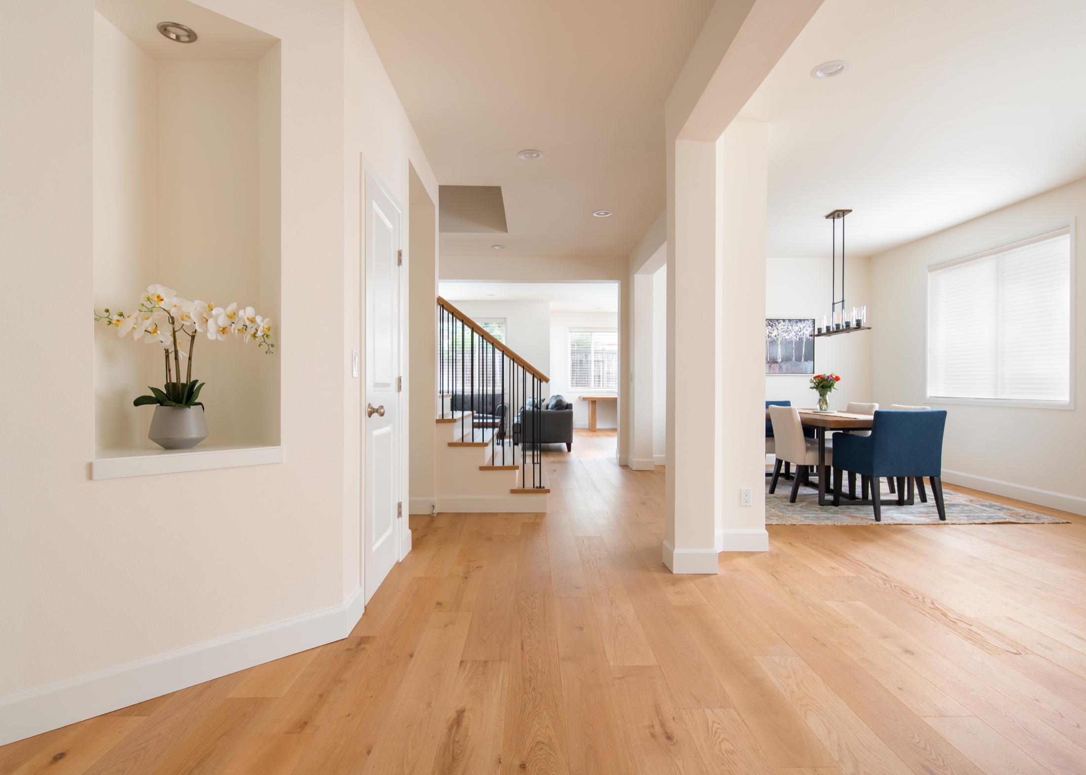 Entry, stairs and dining area connected by light wood flooring in a completed LeviArs renovation