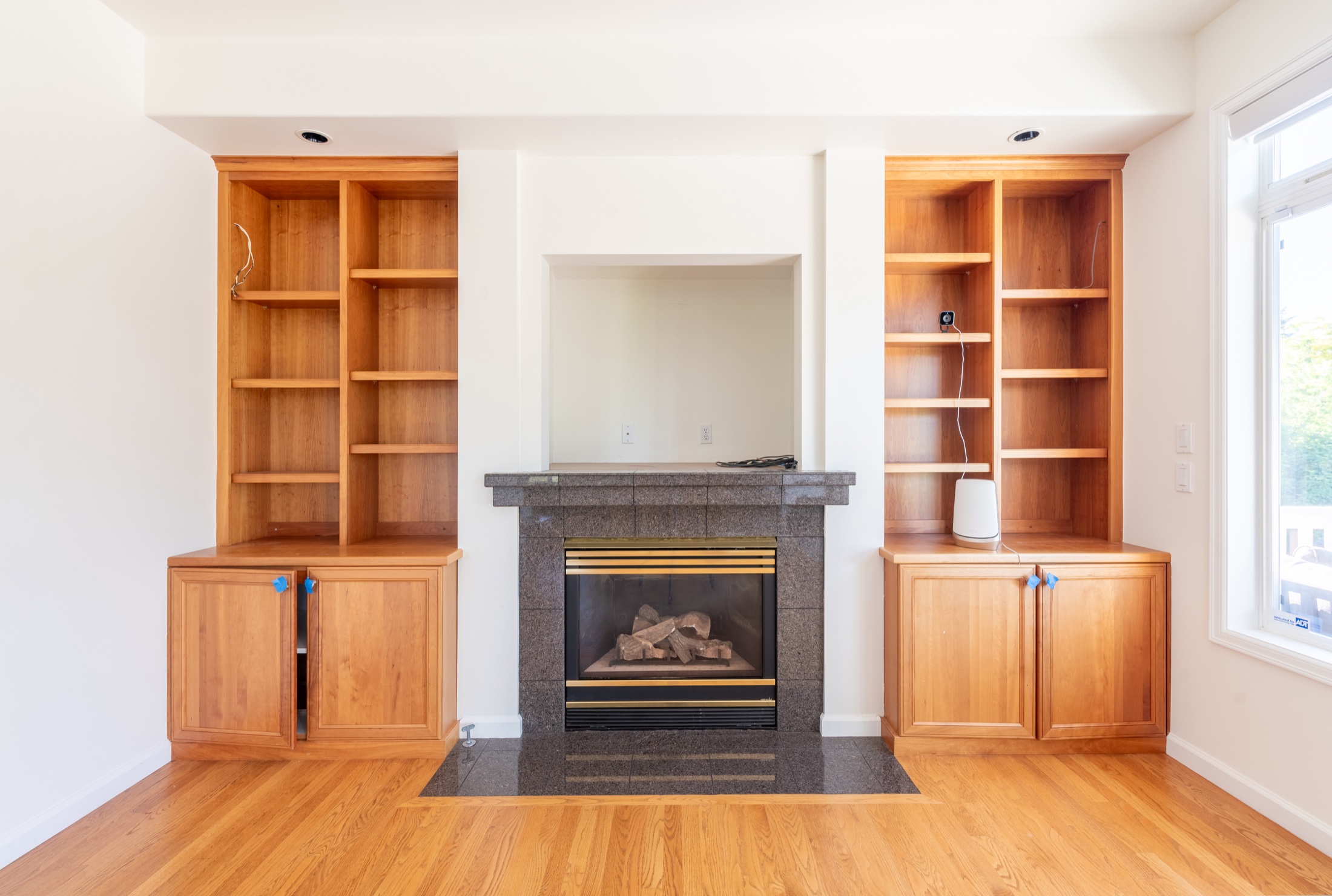 Klee fireplace before remodeling with a dark tiled surround, raised mantel detail, television niche and tall wood cabinetry