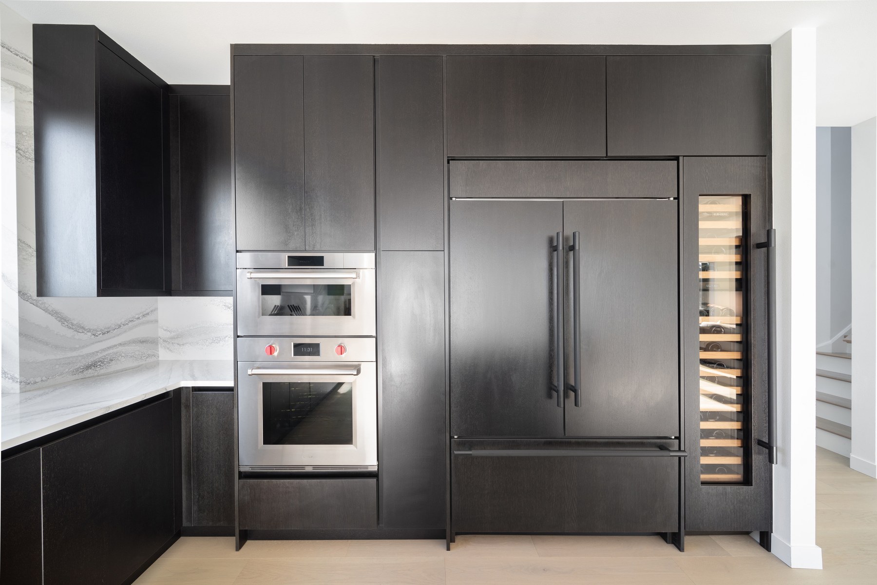 Close-up of coordinated cabinet fronts, refrigerator panels, wine storage and wall ovens in the Klee kitchen