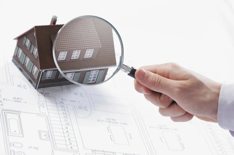 Magnifying glass over a model house and architectural floor plans