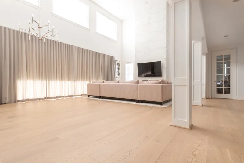 Tall living room with pale oak flooring, full-height curtains and a fireplace wall