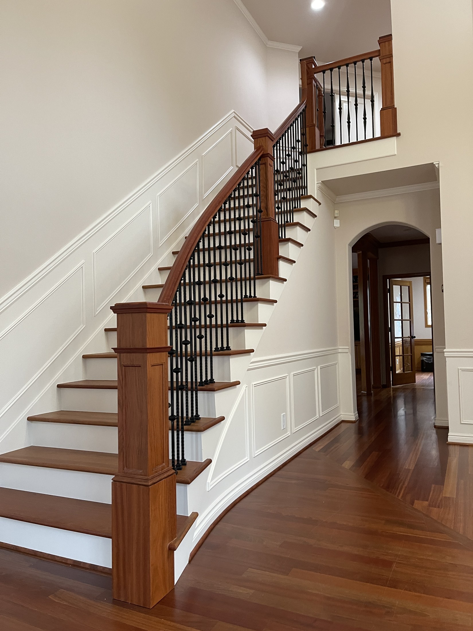 Traditional staircase with warm wood treads and posts, white risers and decorative dark metal balusters