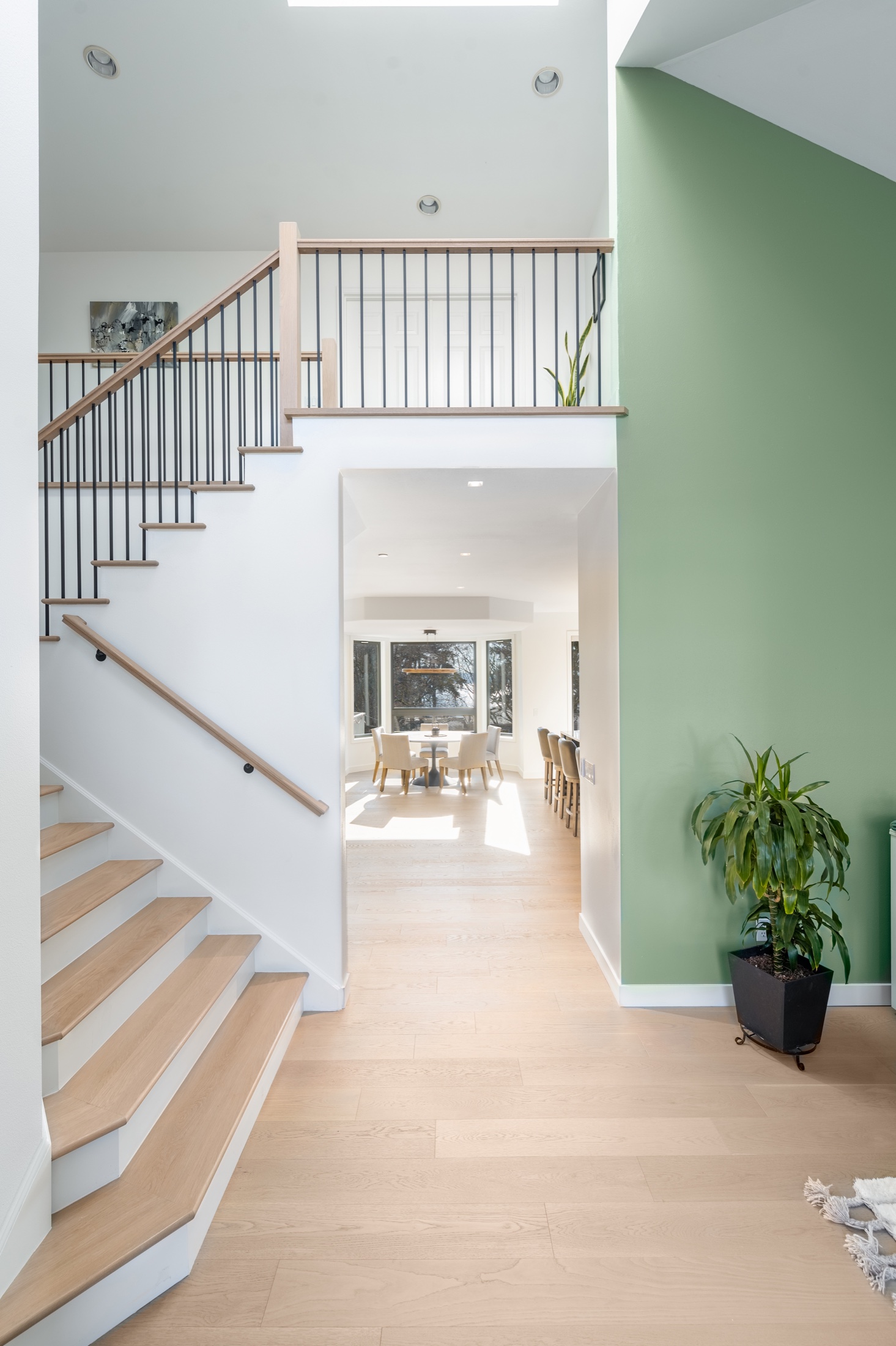 Klee staircase and entry with light wood flooring continuing toward the dining room