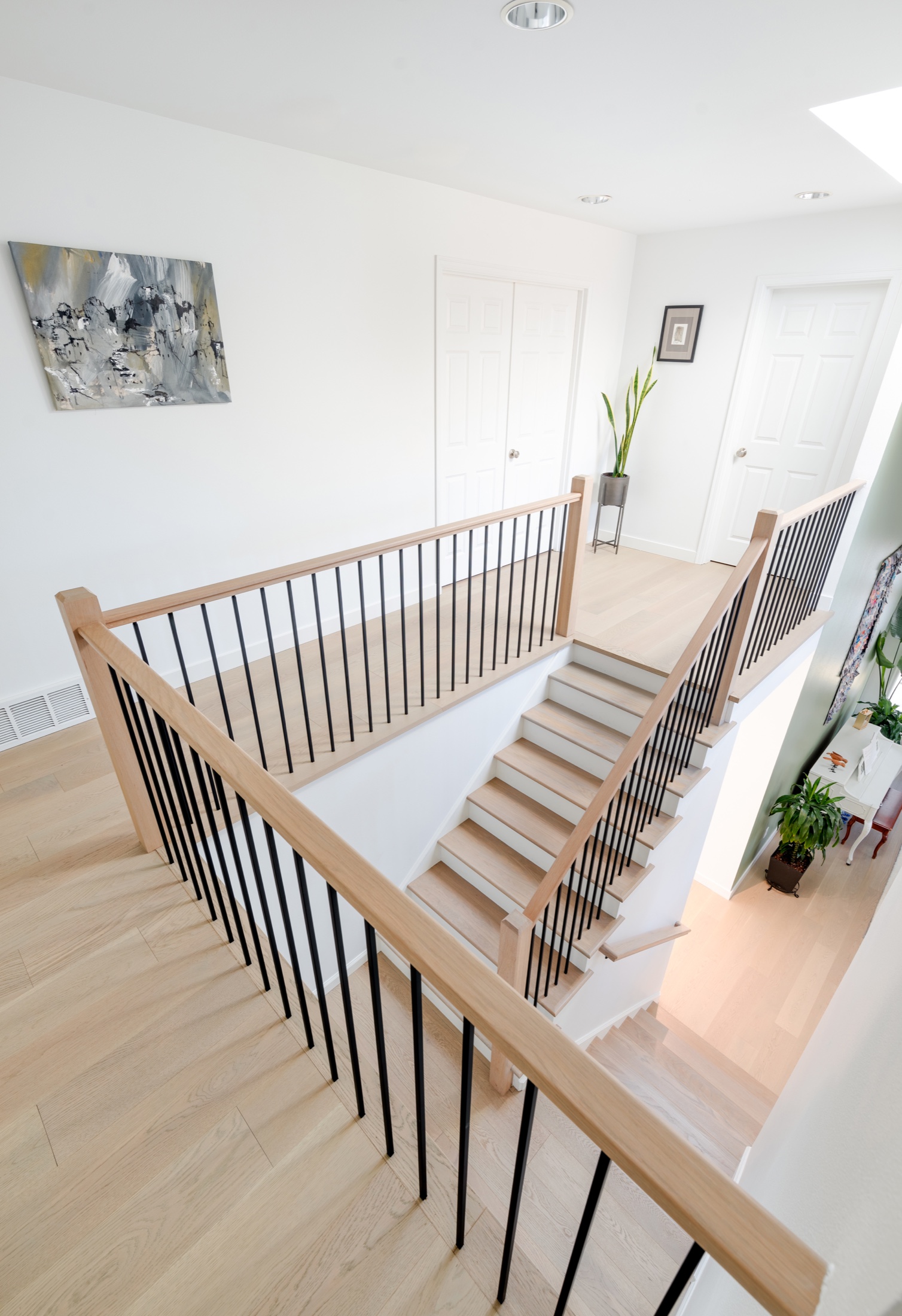View from the Klee upper landing showing wood handrails, square posts, dark balusters and the stair-to-floor transition