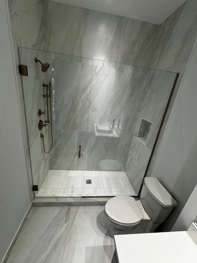Glass shower with light marble-look tile and recessed niche in Bellevue, Washington