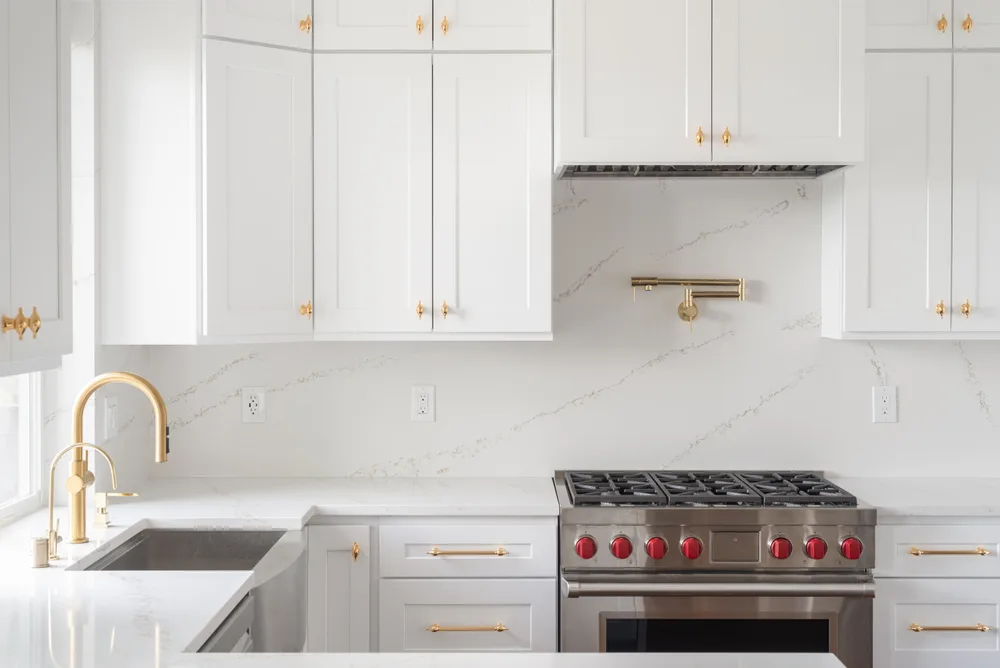 Apron-front sink and range with warm metal fixtures and white cabinetry in Issaquah, Washington