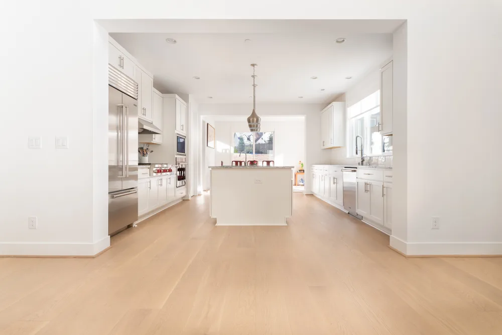 White kitchen and island connected by light wood flooring in Woodinville, Washington